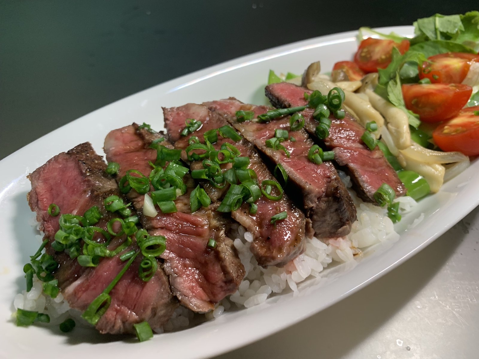 ご飯の上に並べた和牛ヒレのステーキと小ねぎ